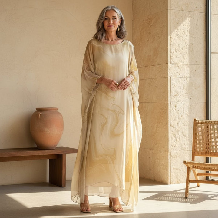 Woman wearing beige floaty batwing maxi dress on sunlit patio
