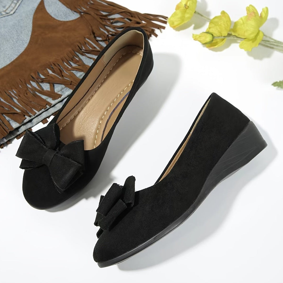 Gray suede bow ballet flats worn on crossed feet with shell anklet