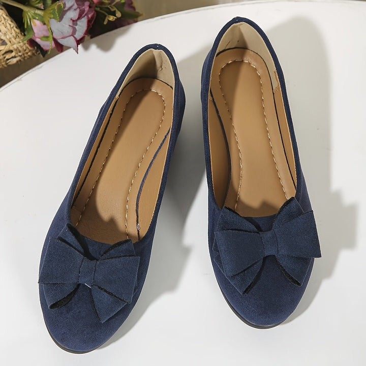 Brown suede bow ballet flats shown from above with beaded anklet