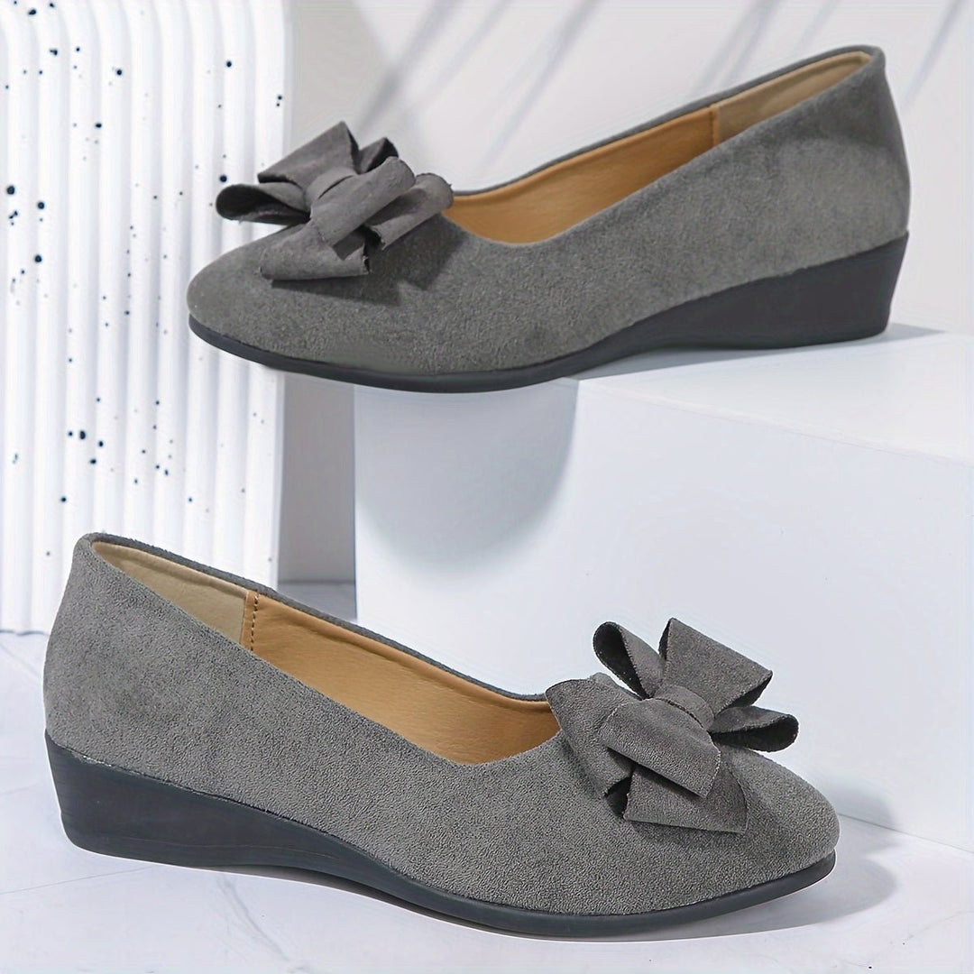 Navy suede bow ballet flats shown from heel with gold ankle chain