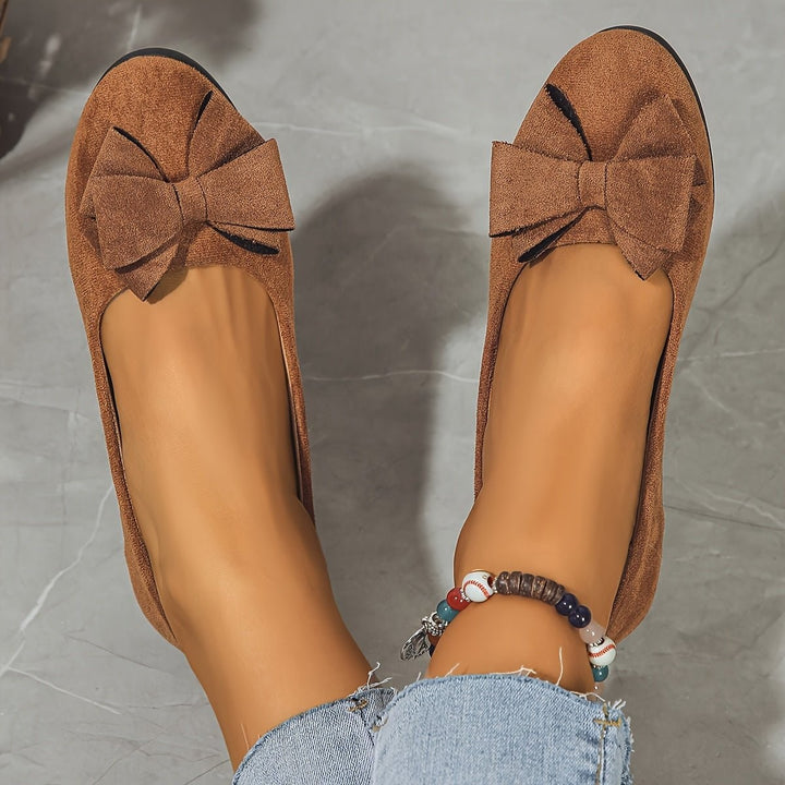Black suede low wedge ballet flats shown from heel with beaded anklet