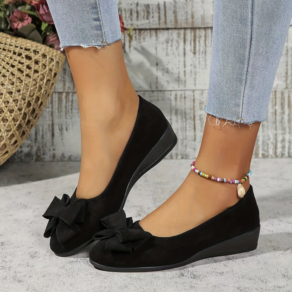Black suede low wedge ballet flats with bow detail and ankle bracelet