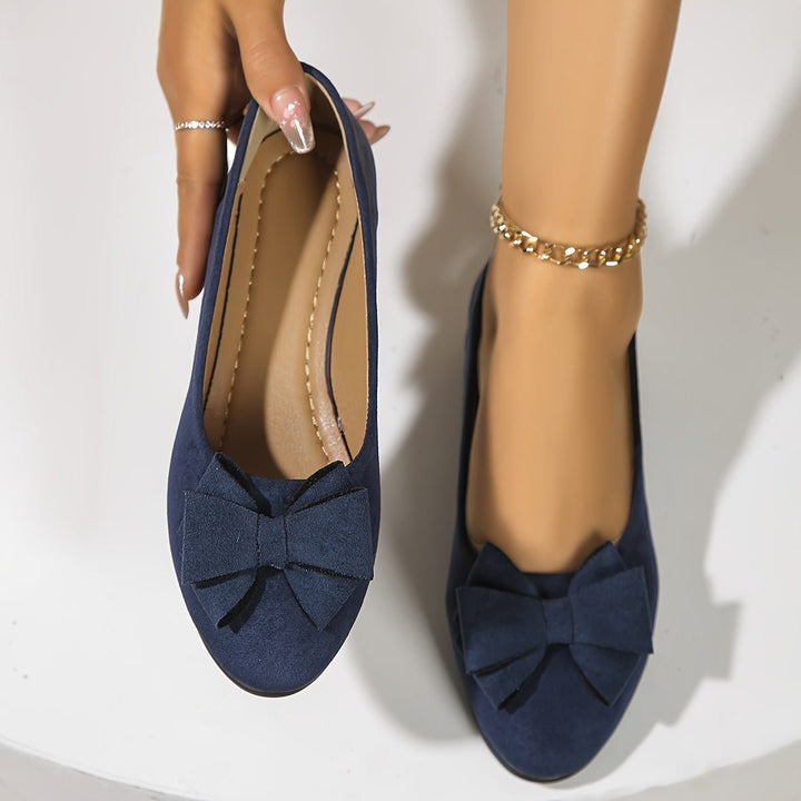 Gray suede bow ballet flats shown from behind with beaded anklet