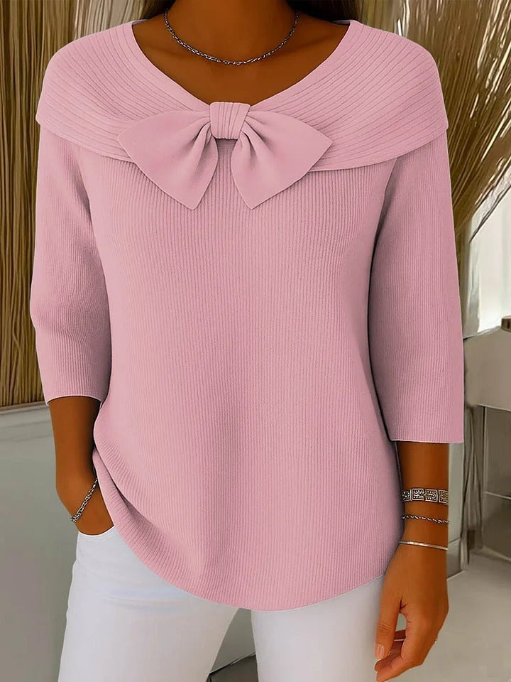 Pink ribbed knit top featuring bow accent and folded collar neckline