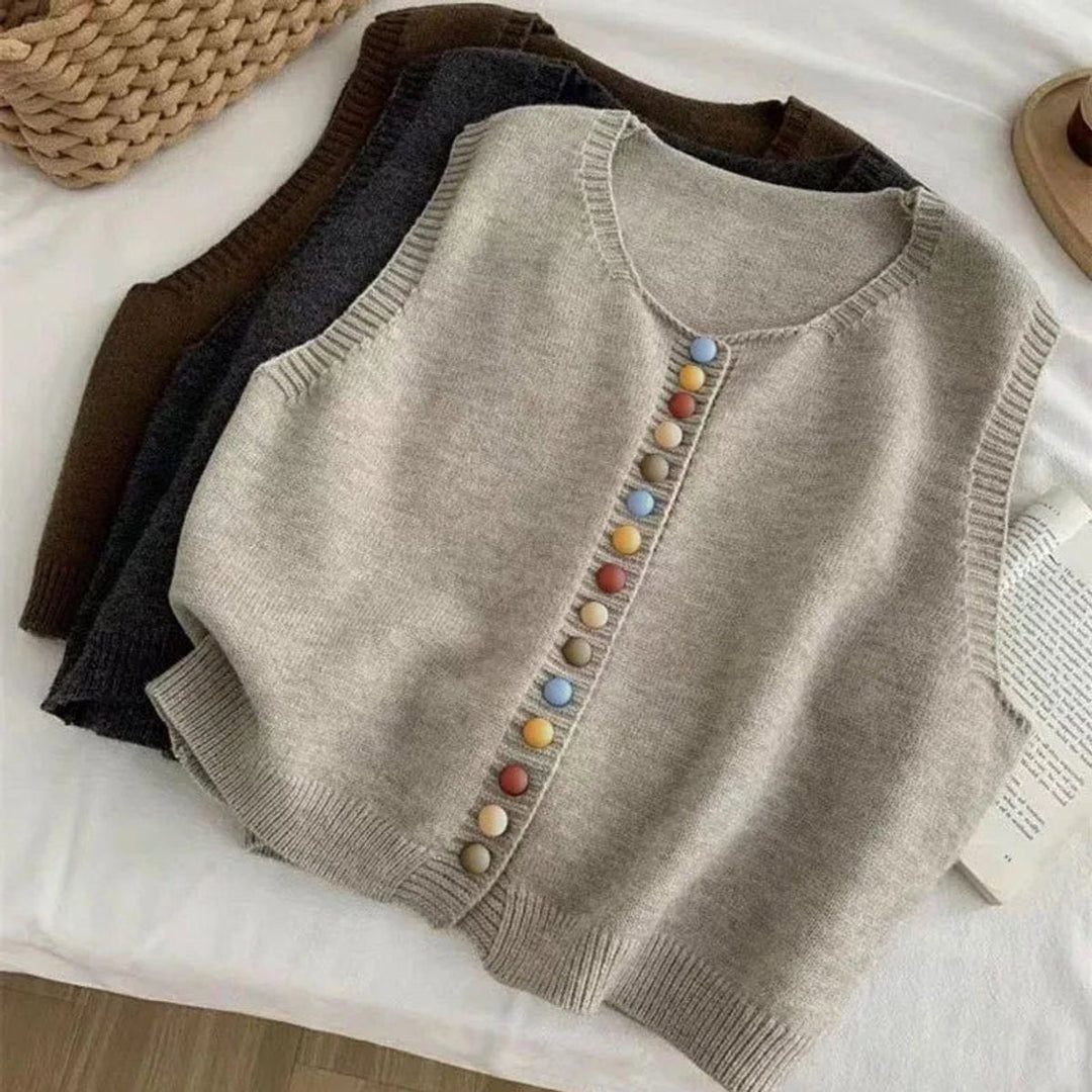Beige, charcoal, and brown knit vests stacked showing button detail