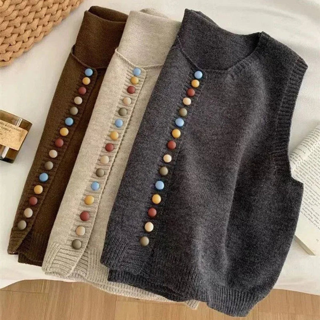 Three knit sweater vests in brown, gray, and tan with colorful buttons