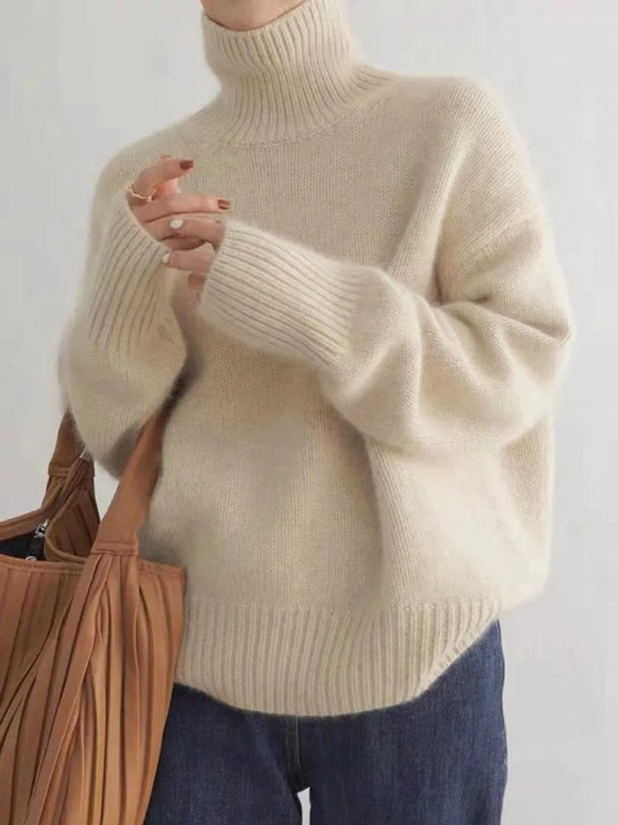 Cream oversized turtleneck sweater with ribbed cuffs, paired with denim jeans