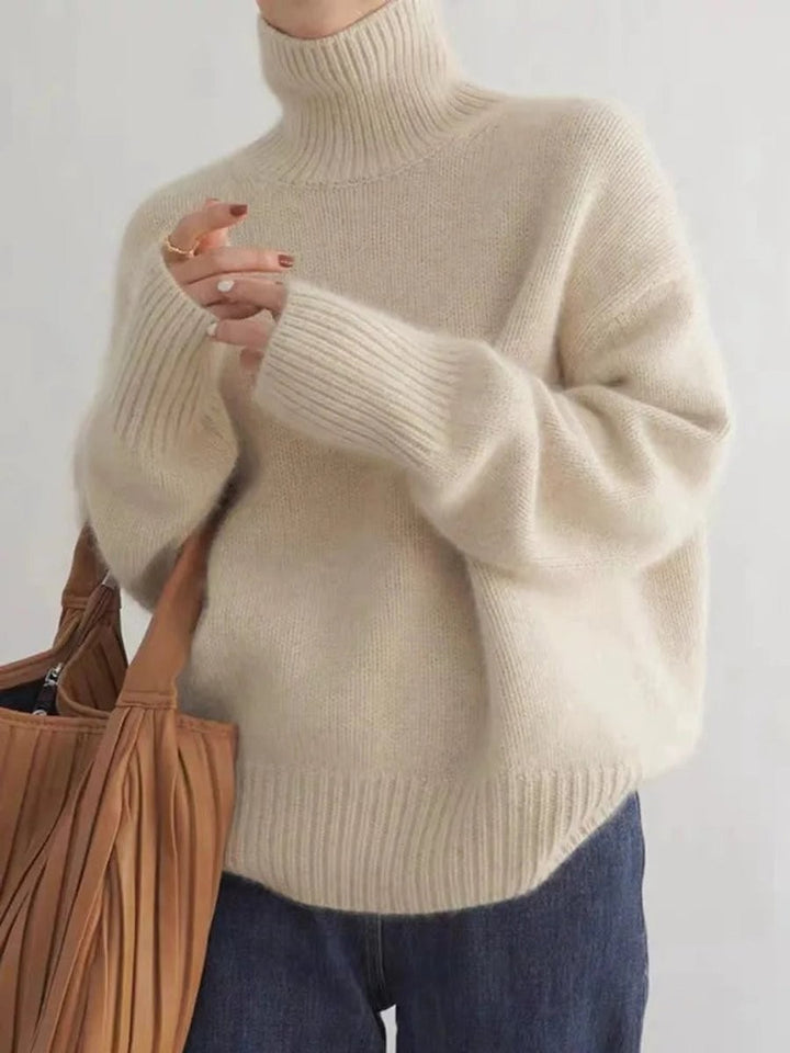 Cream oversized turtleneck sweater with ribbed cuffs, paired with denim jeans