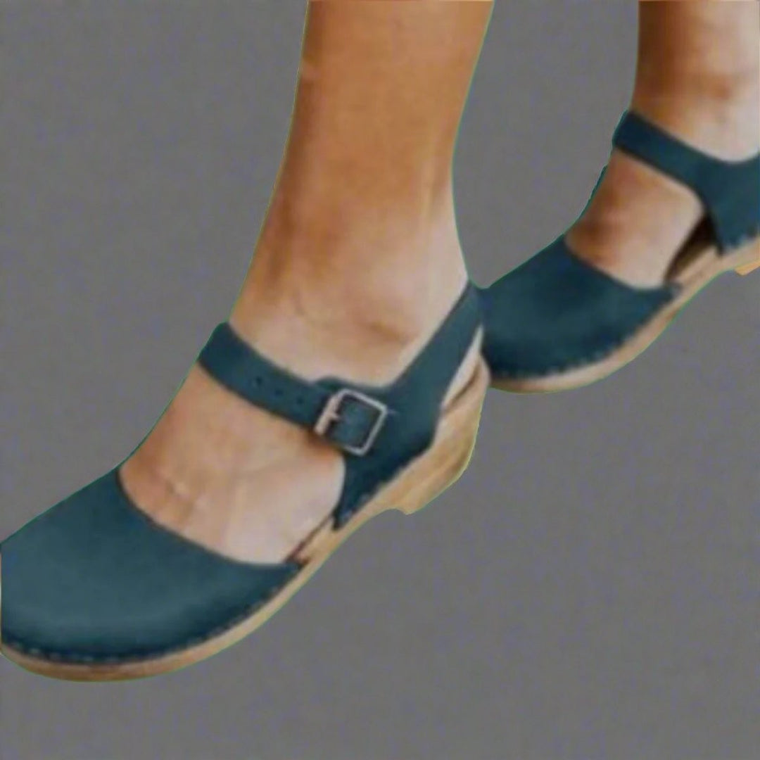 Teal suede ankle-strap clogs featuring wooden platform sole and buckle detail