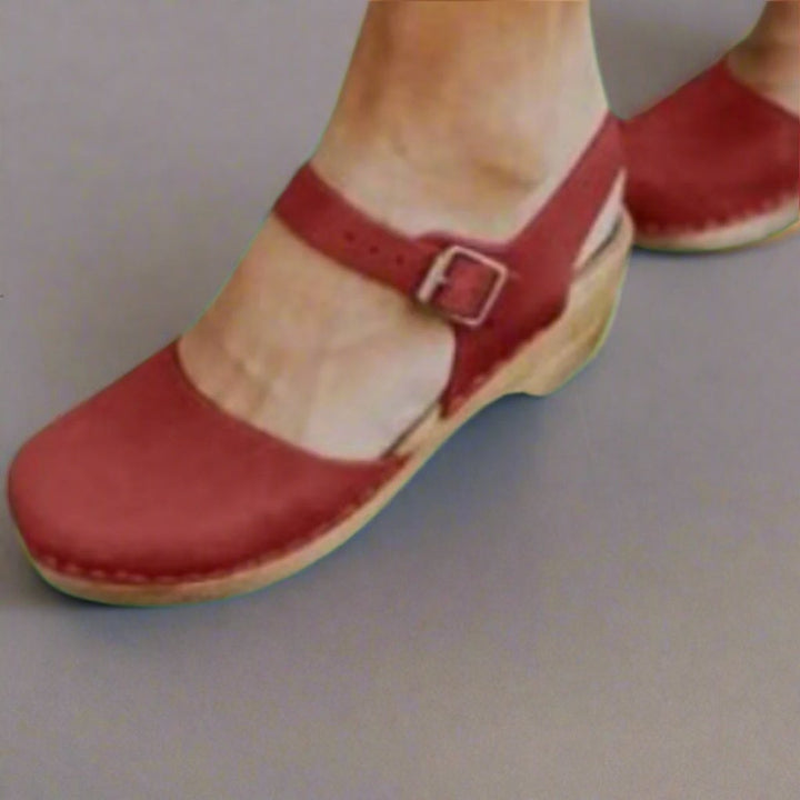 Red suede ankle-strap clog with wooden platform heel, close-up front view