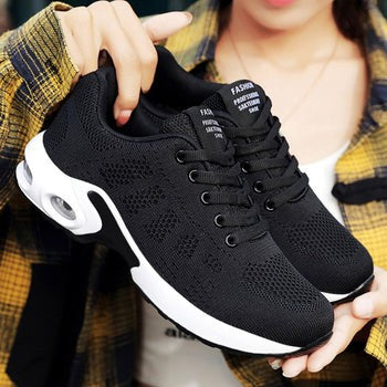 Woman holding black mesh sneaker showing air-cushioned sole detail