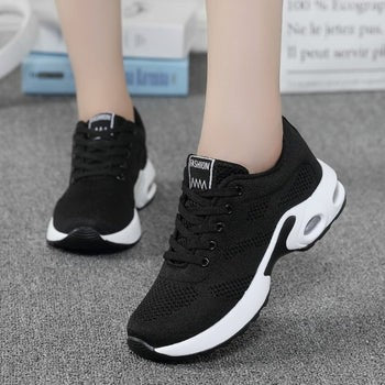 Black and white knit sneaker displayed standing on light gray floor