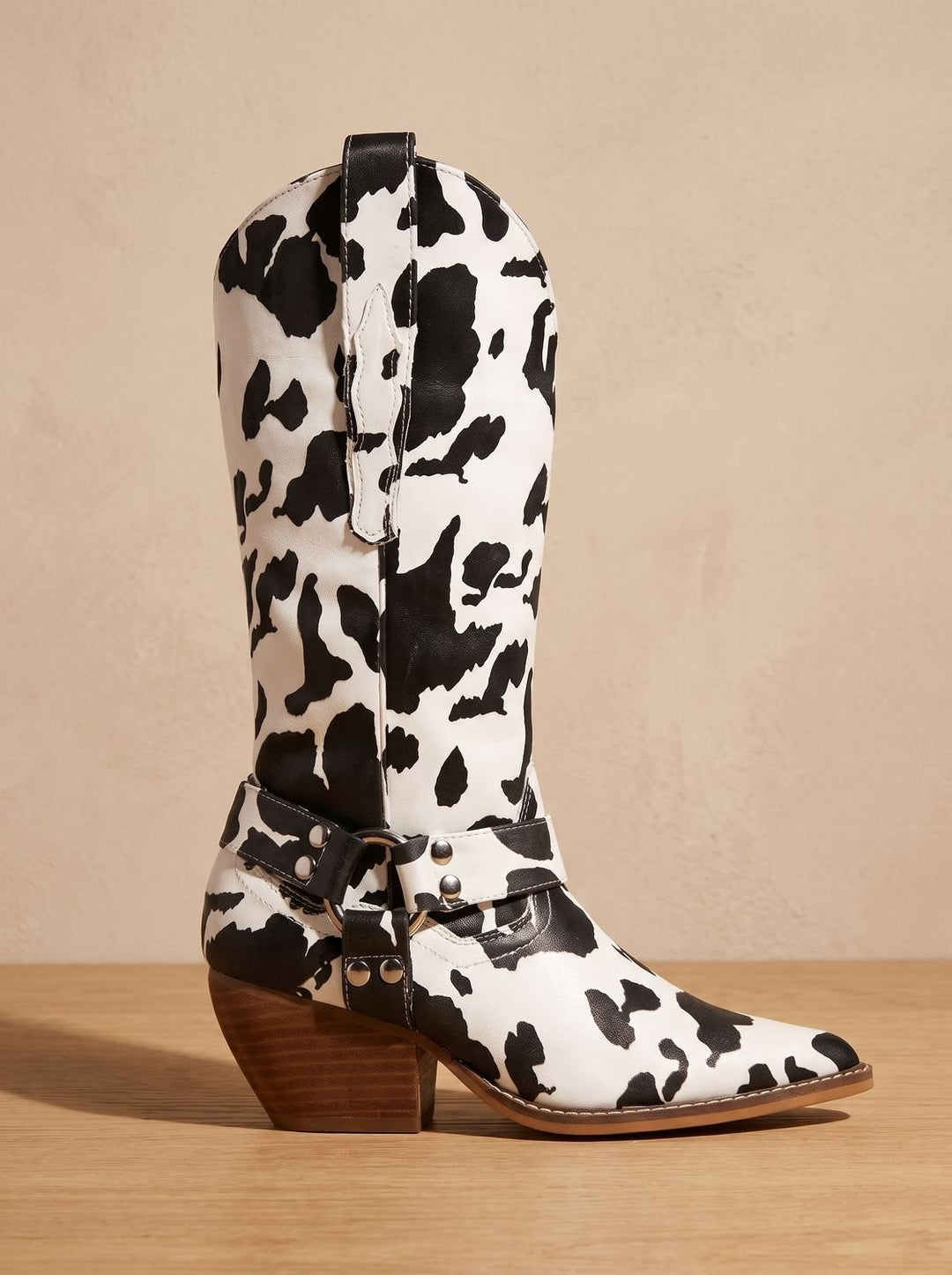 Black and white cow-print western boot with harness strap and block heel
