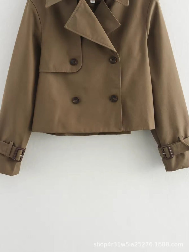 Close-up of brown cropped double-breasted trench coat with buckle cuffs
