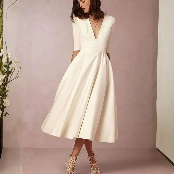 Model wearing ivory V-neck midi dress with pleated flowing skirt