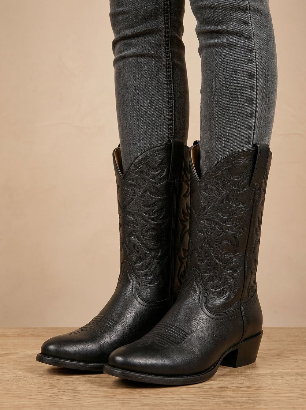 Black leather cowboy boots with embroidered shaft worn with gray skinny jeans