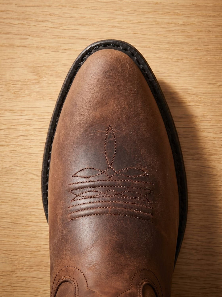 Close-up of brown leather cowboy boot toe with decorative stitched design