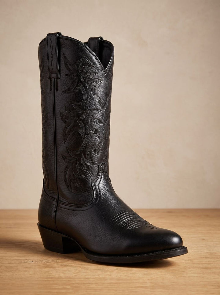 Black leather cowboy boot toe close-up showing smooth grain and stitch pattern
