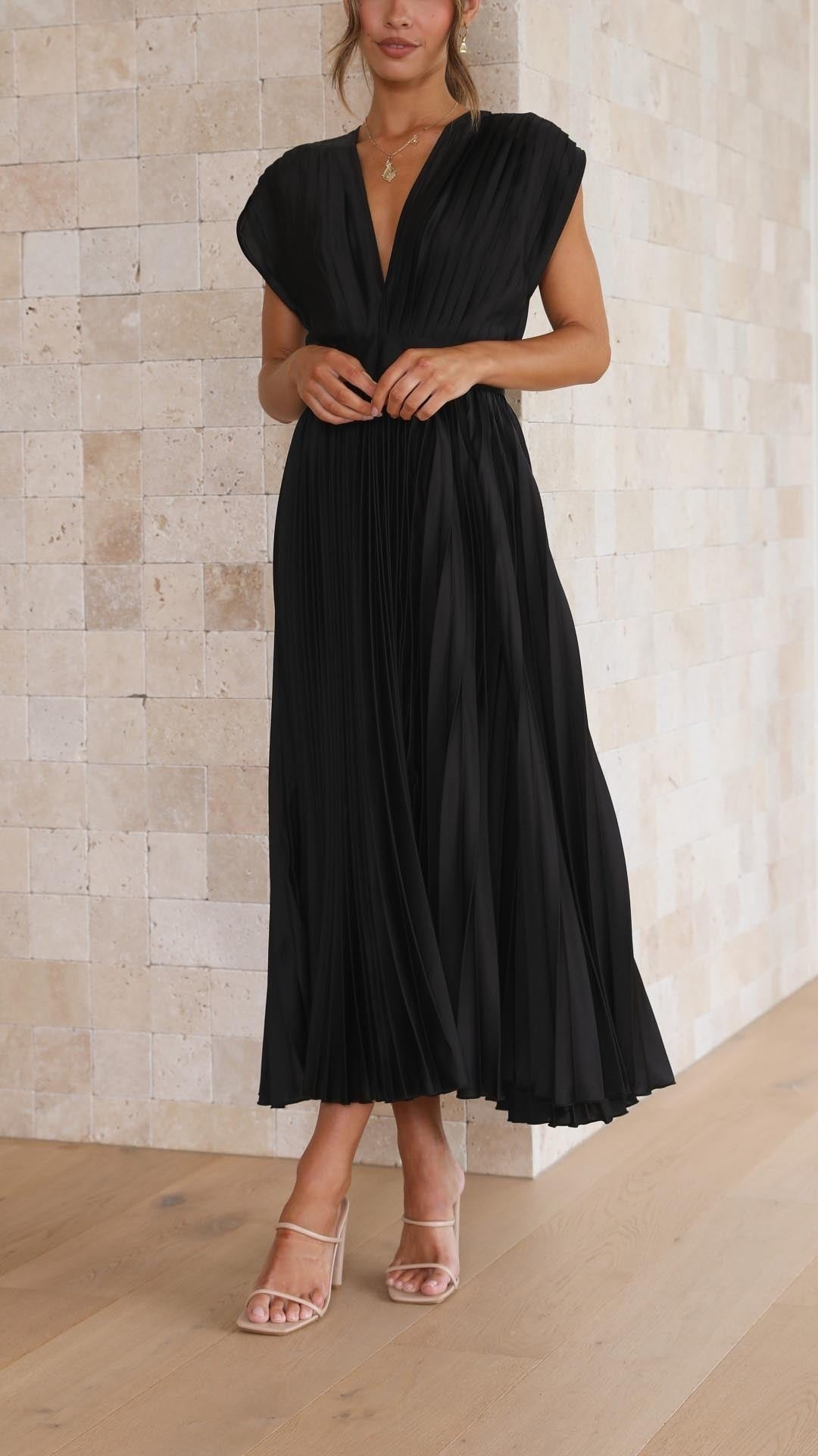Close-up front view of black pleated dress with deep V-neck