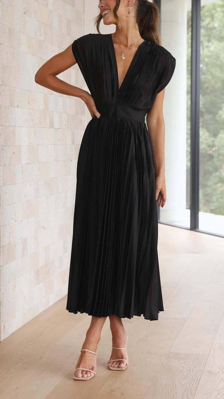 Black pleated satin dress flowing mid-twirl with cap sleeves