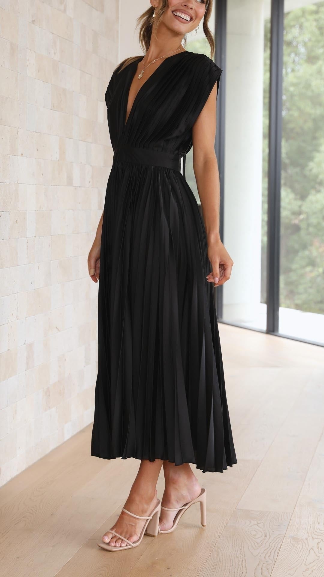 Back view of black pleated dress with open back and tie strap