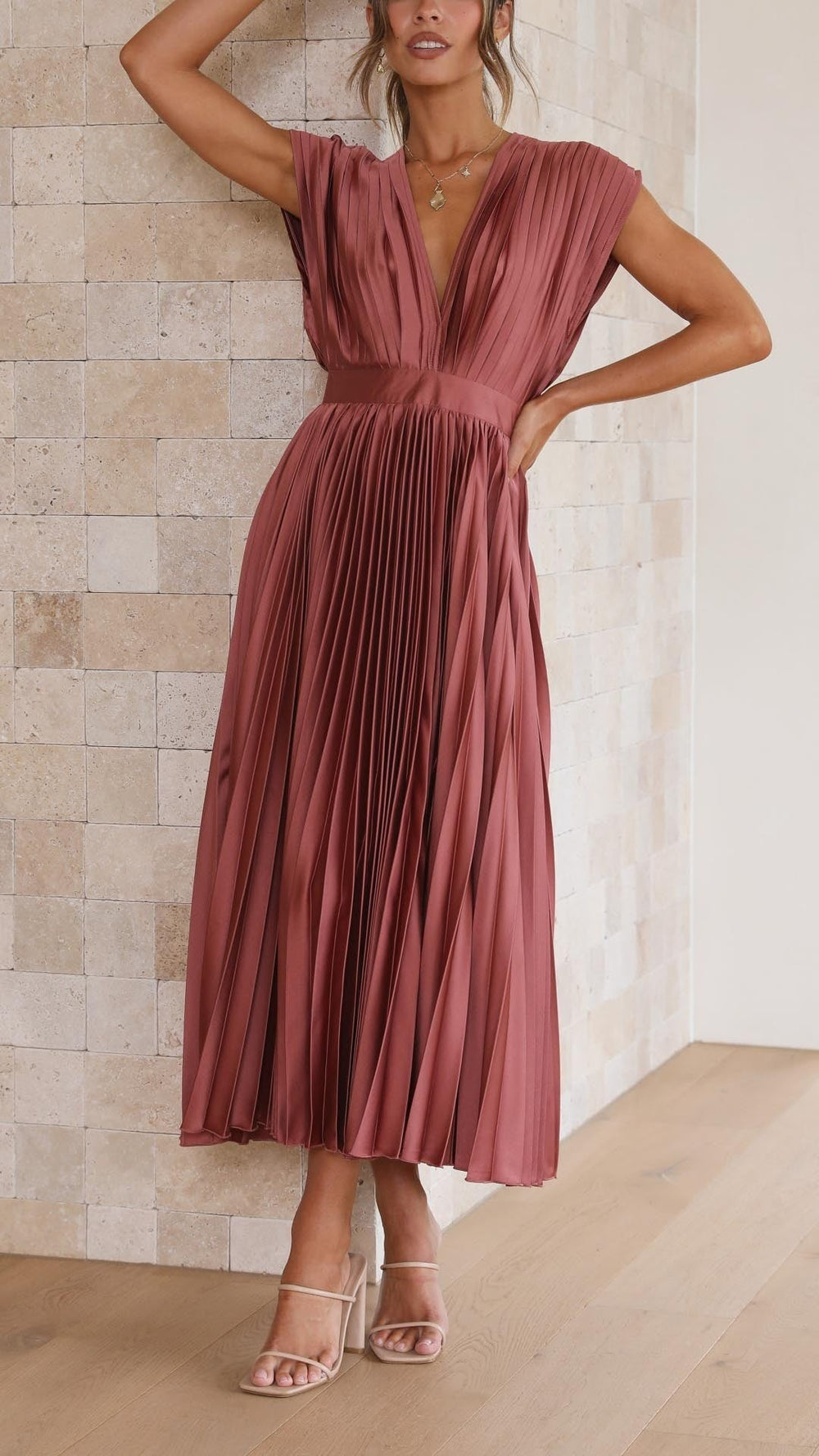 Model wearing rust satin pleated midi dress with deep V-neckline