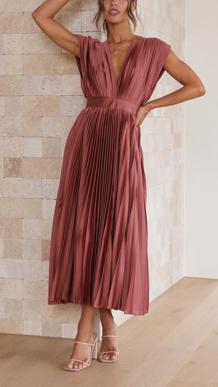 Model wearing rust satin pleated midi dress with deep V-neckline