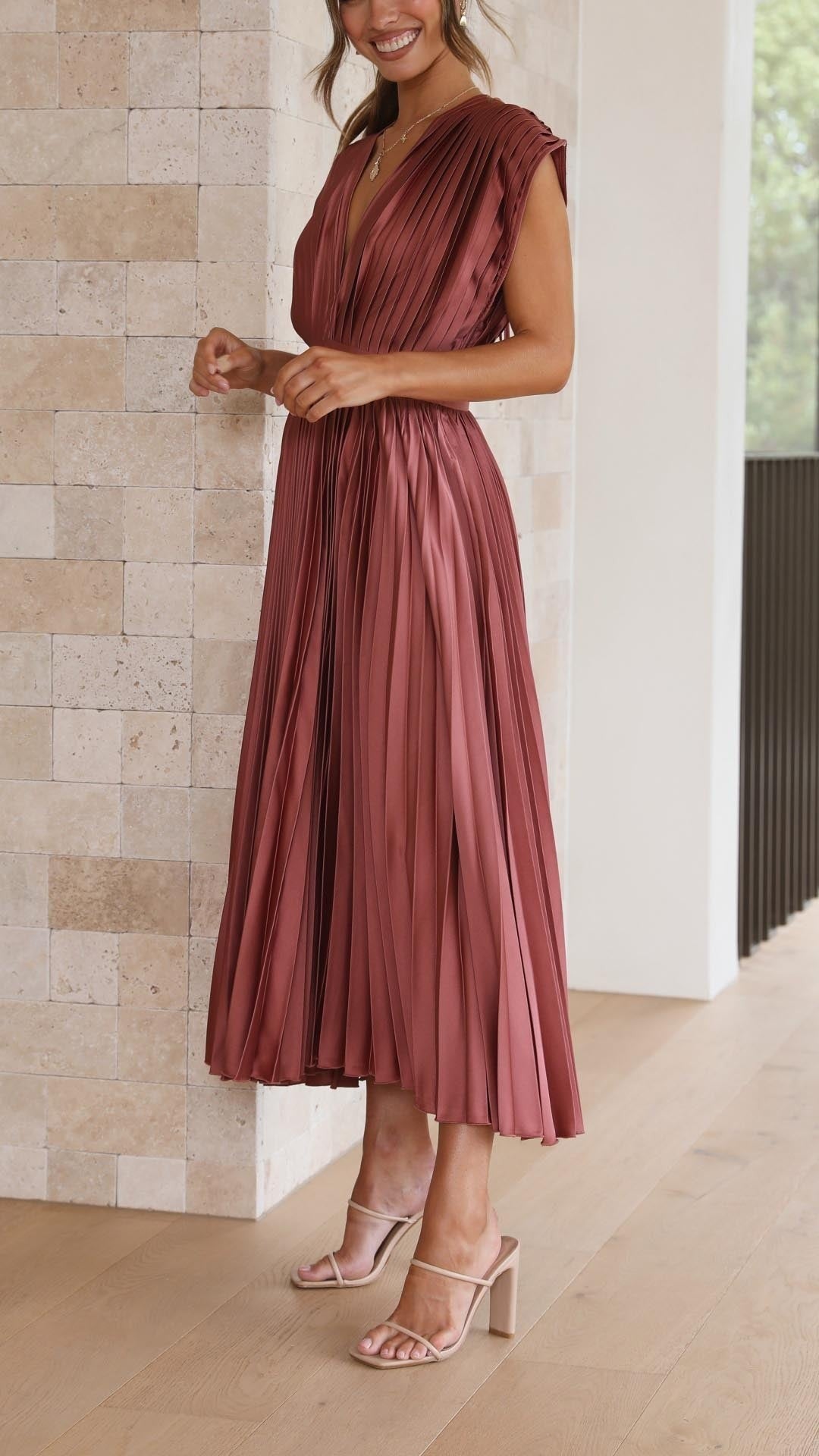Side profile of rust satin pleated dress with flowing skirt