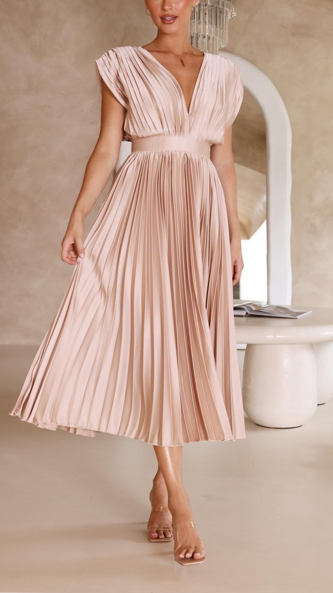 Side view of blush satin pleated dress with cap sleeve design