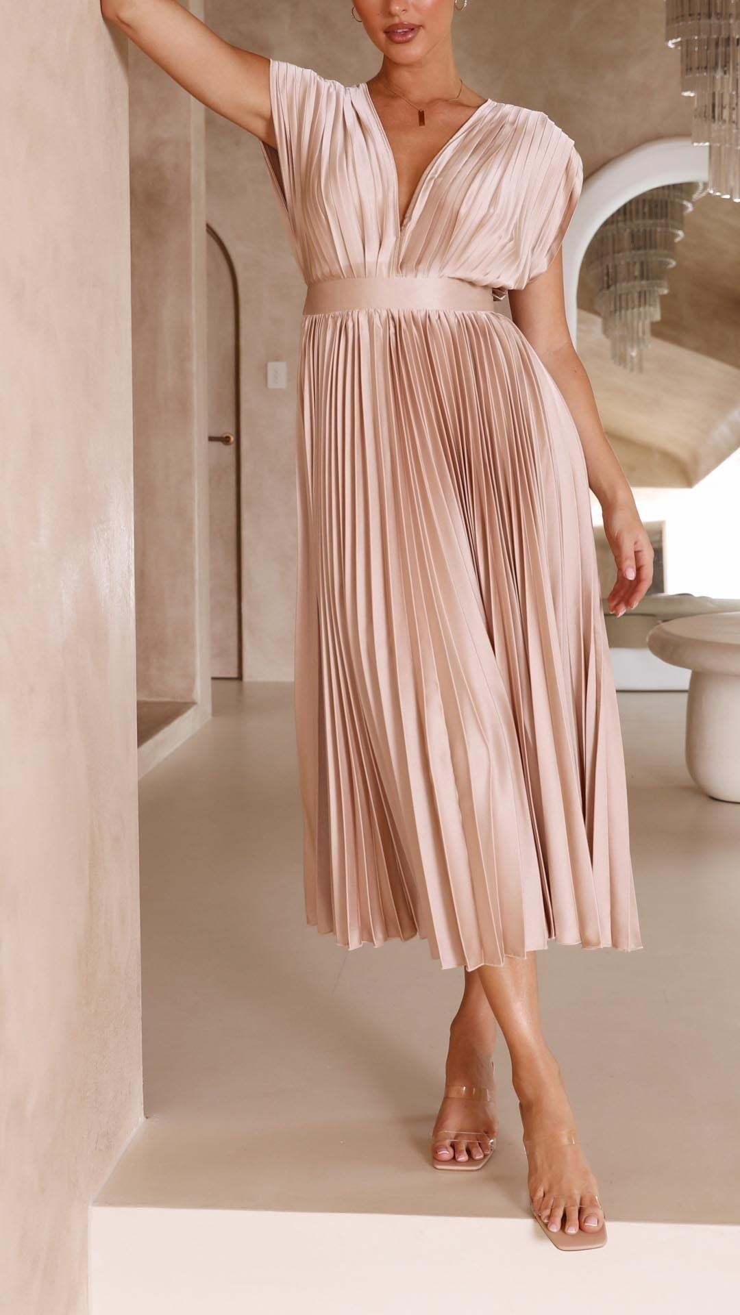 Model adjusting waistband on champagne pleated satin midi dress
