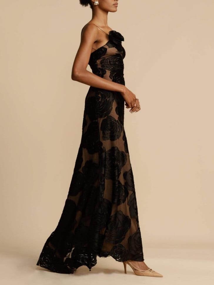 side view of black rose-appliqued mermaid gown with sheer skirt panels
