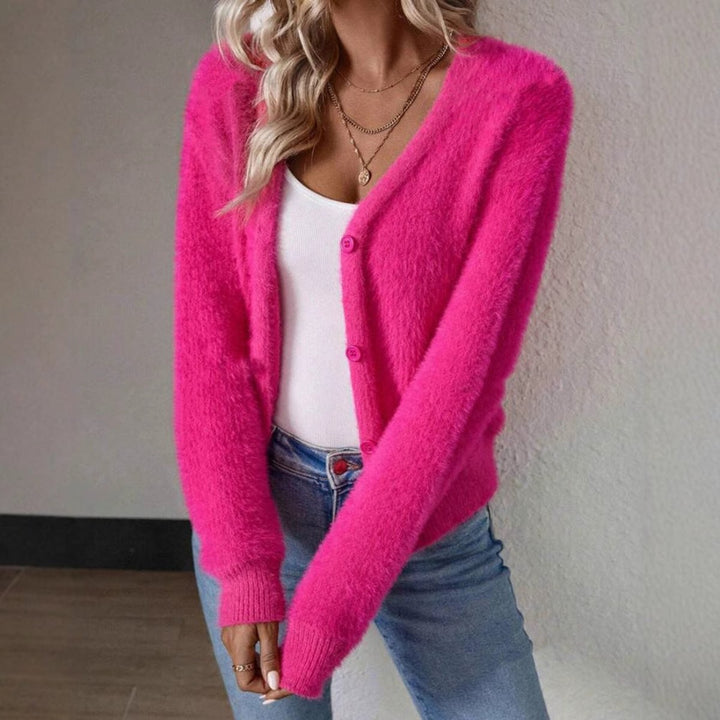 Hot pink fuzzy cardigan sweater paired with denim jeans and gold jewelry
