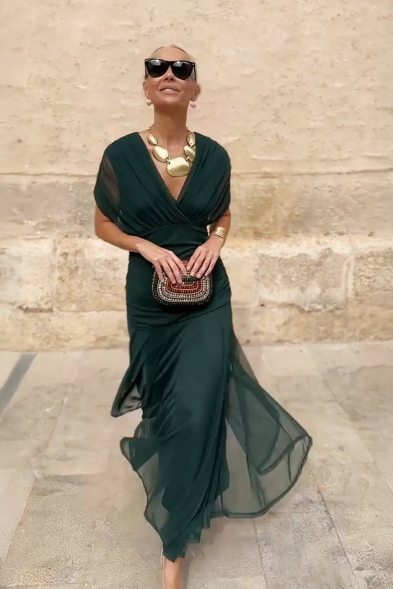 Model walking in dark green mesh maxi dress with flowing tiered skirt