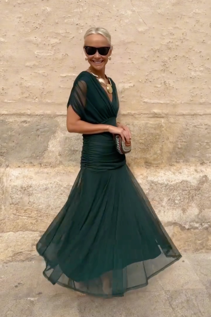 Twirling dark green flutter sleeve maxi dress with sheer flowing hemline
