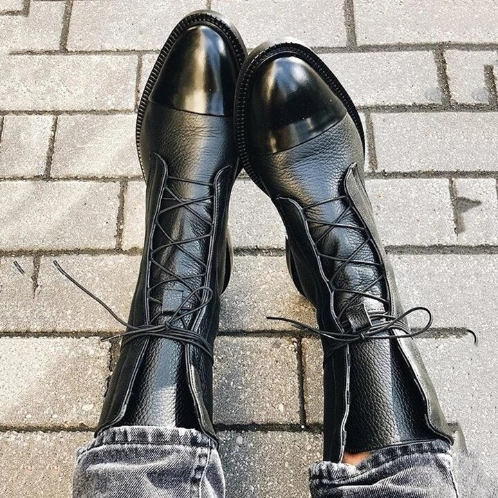Black leather lace-up boots viewed from above on cobblestone pavement