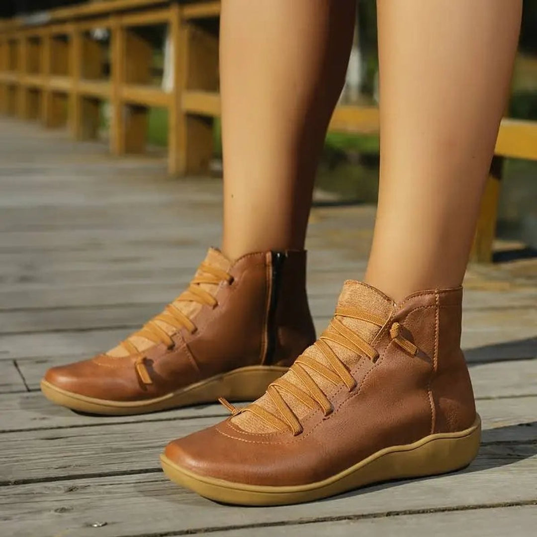 Woman wearing tan leather lace-up ankle boots on wooden boardwalk