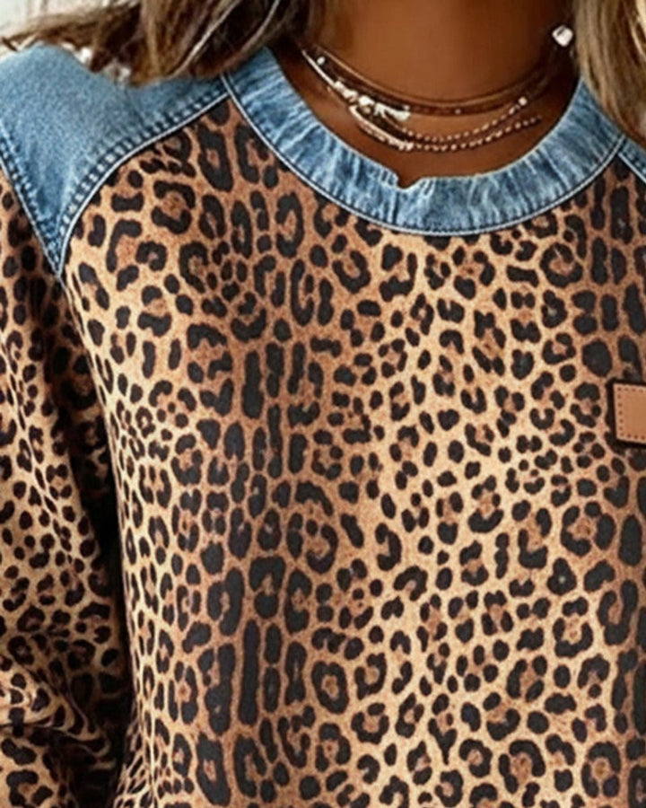 Close-up of leopard print sweater with denim shoulder trim and crew neckline