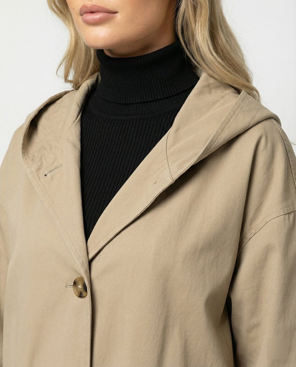 Close-up of beige trench coat hood, lapel, and button detail