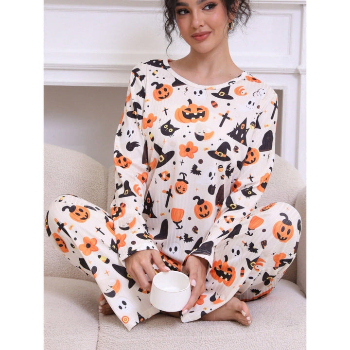 Woman sits cross-legged in pumpkin-print pajama loungewear holding a small cup