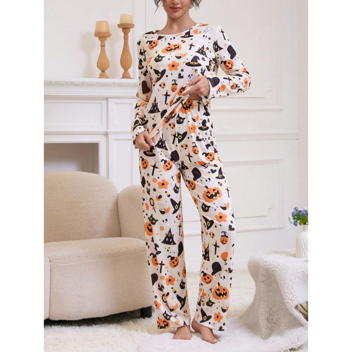 Woman stands showcasing wide-leg pajama pants with orange pumpkin and bat print