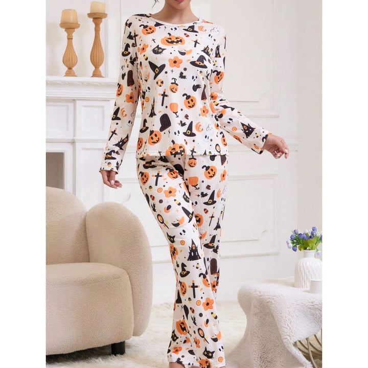 Woman models cream pajama top and pants with witch hat and ghost graphics