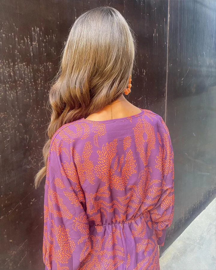 Back view of purple and orange print dress with elastic waist and long sleeves