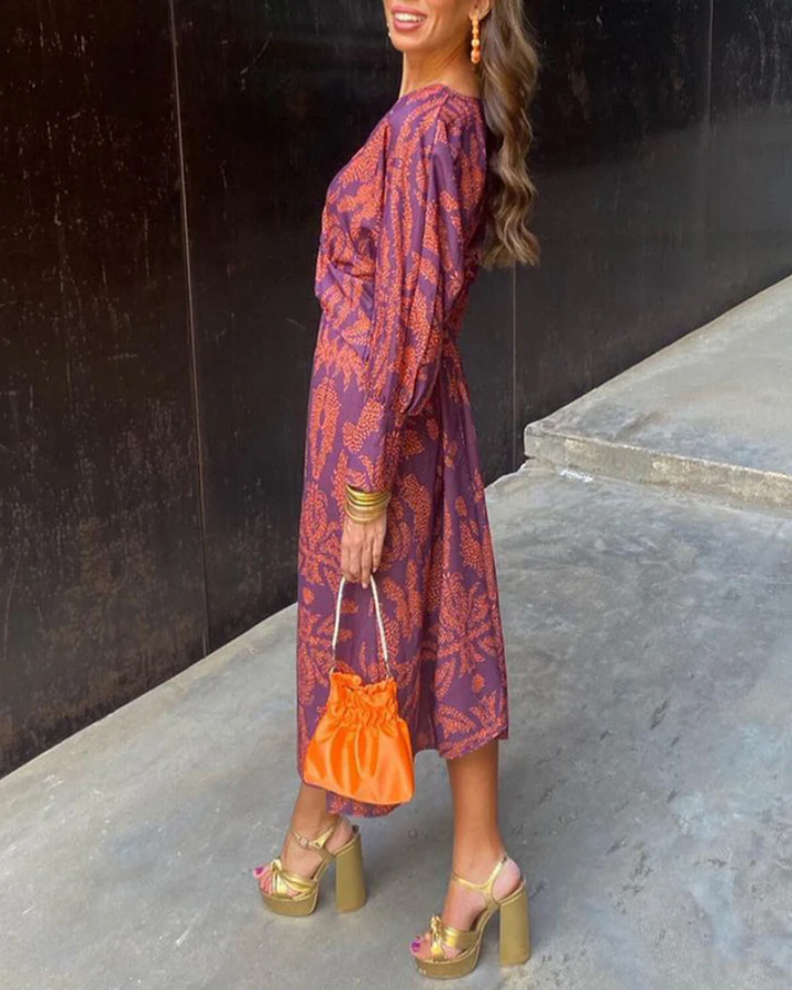 Purple floral print midi dress styled with gold platform sandals and orange clutch