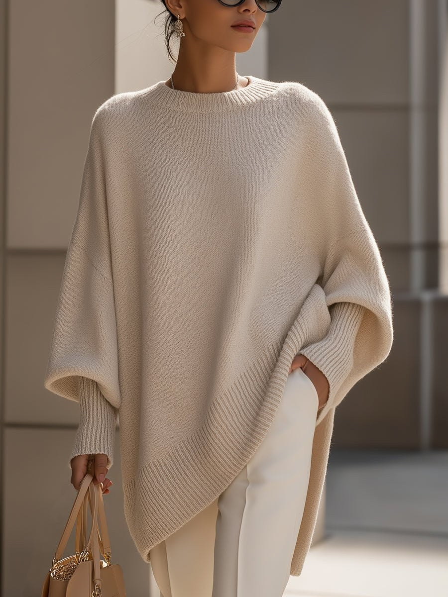 Beige oversized batwing sweater with ribbed asymmetric hem, styled with white pants