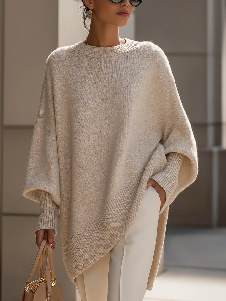 Beige oversized batwing sweater with ribbed asymmetric hem, styled with white pants