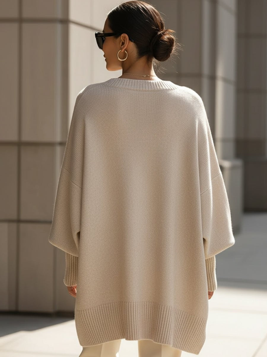Back view of beige oversized batwing sweater with ribbed hem, worn with bun hairstyle