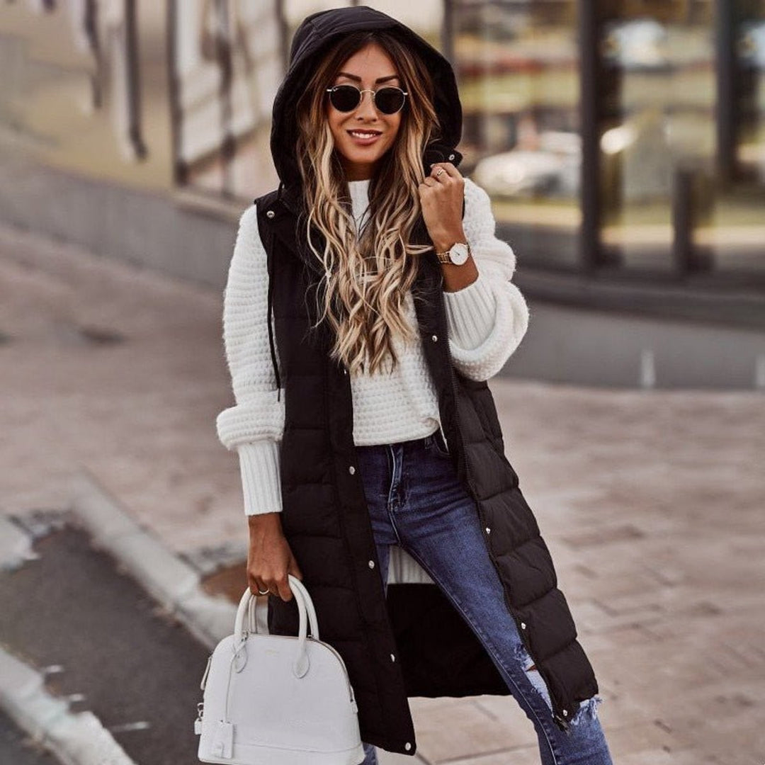 Black hooded quilted puffer vest layered over a white knit sweater