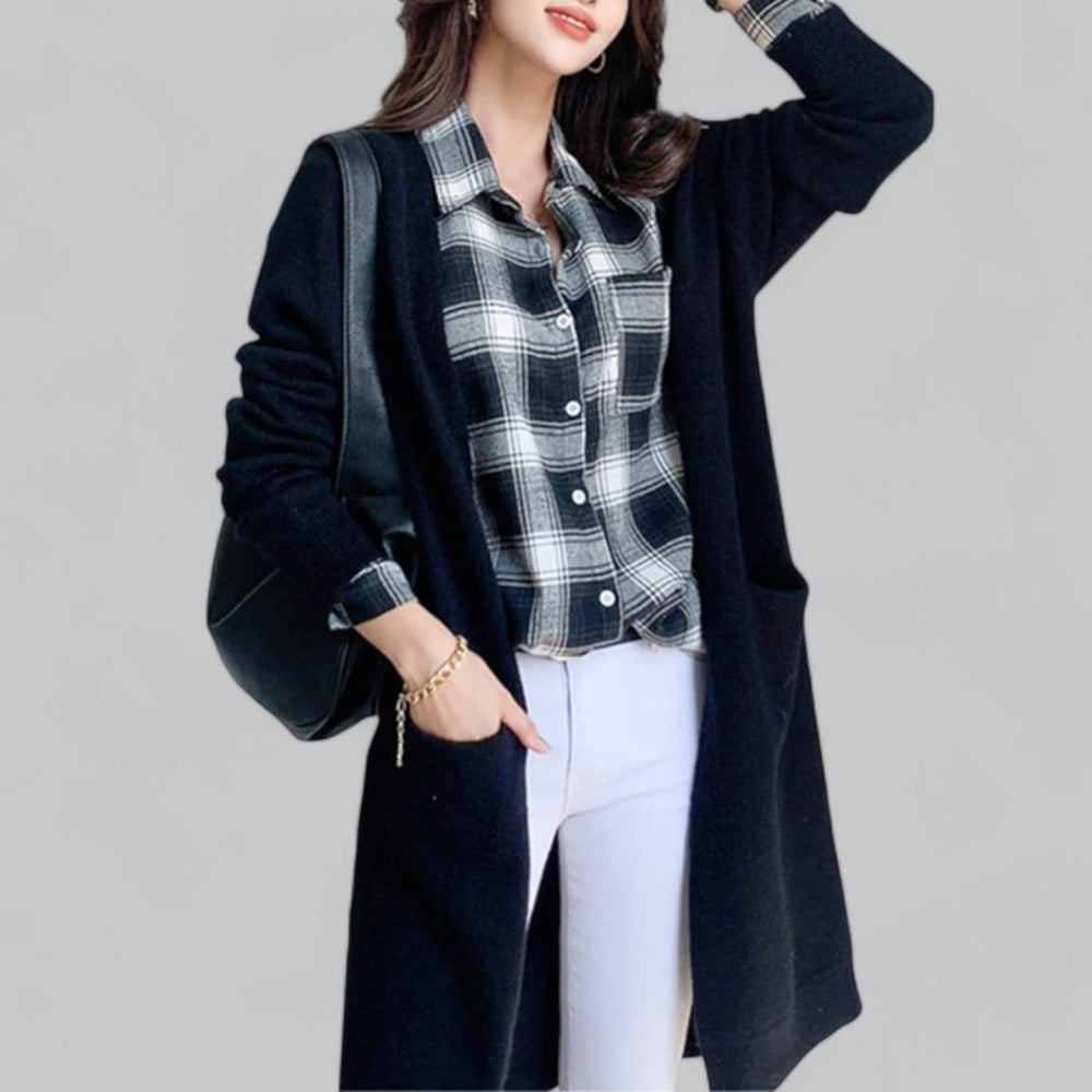 Black long knit cardigan worn over plaid shirt and white jeans