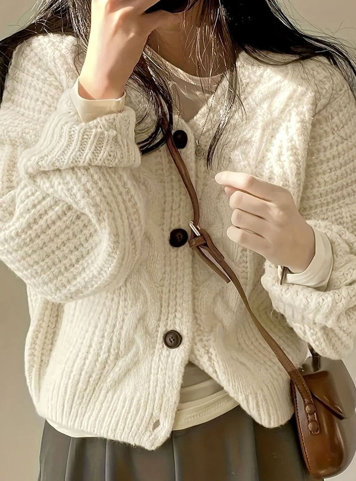 chunky cable-knit cream cardigan with dark buttons and ribbed cuffs detail