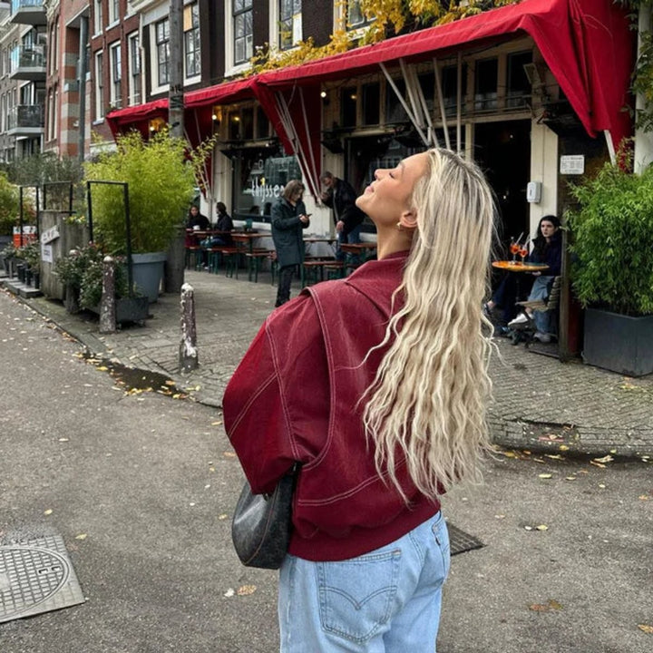 Back view of burgundy contrast-stitch bomber jacket paired with light wash jeans